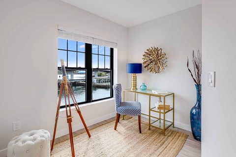 a living room with a large window and a desk with a chair
