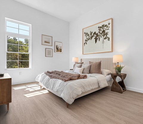 A bedroom with a large bed and a window overlooking trees.