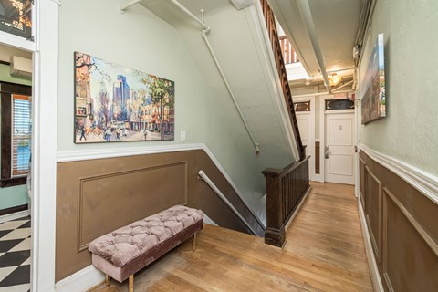 A staircase with a bench and a painting on the wall.