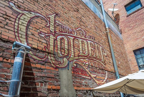 The Old Shoe's sign is on a brick wall.