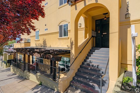 A building with a staircase leading to a black door.