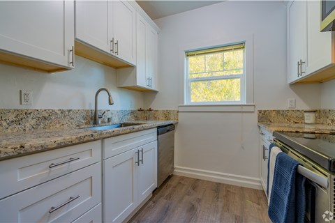 A kitchen with white cabinets and a granite countertop.