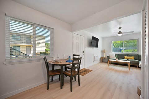 A dining room with a table set for two and a couch in the background.