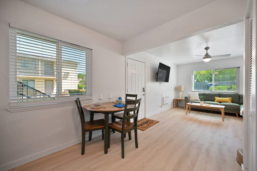 A dining room with a table set for two and a couch in the background.