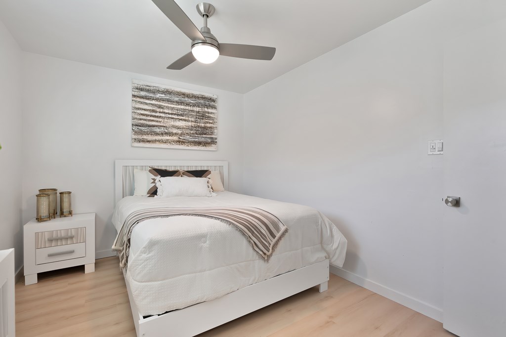 A white bedroom with a large bed and a ceiling fan.