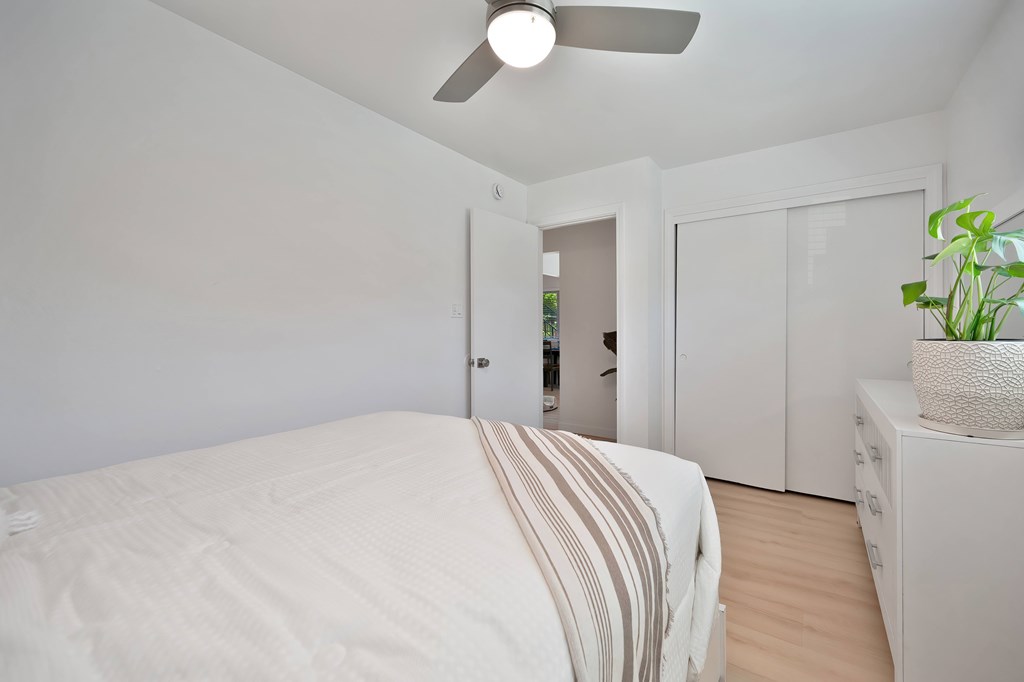 A bedroom with a bed, a ceiling fan, and a cabinet.