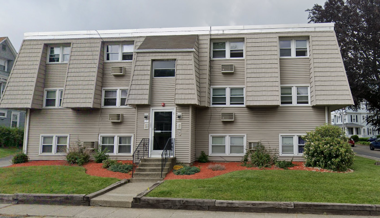 the front of an apartment building with a lawn