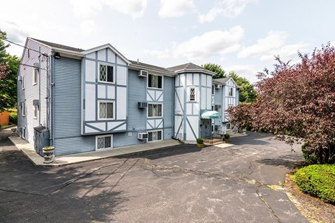 A parking lot in front of a blue building with white trim.