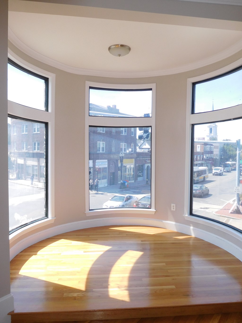 A sunny day in a room with a curved ceiling and three large windows.