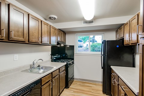 A kitchen with wooden cabinets and black appliances.