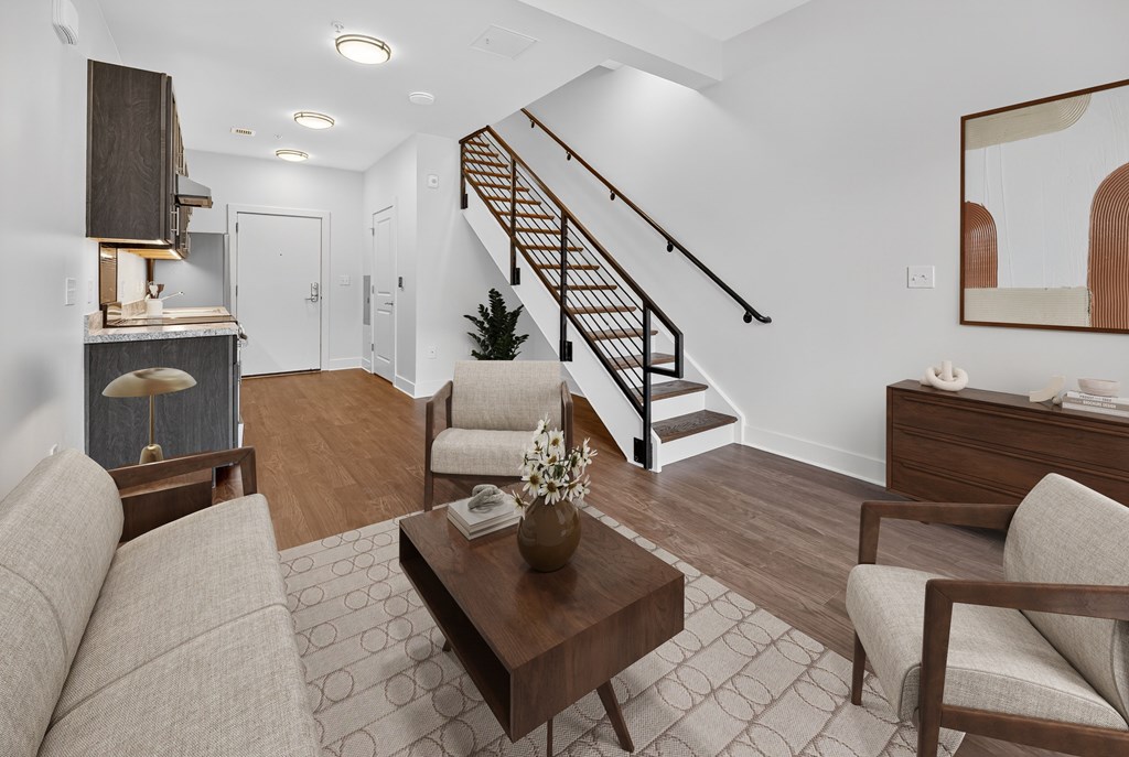 A living room with a brown sofa, a coffee table, and a staircase.