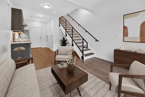 A living room with a brown sofa, a coffee table, and a staircase.