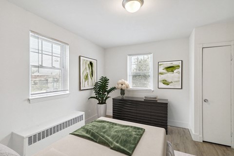 a bedroom with a bed and a dresser and two windows