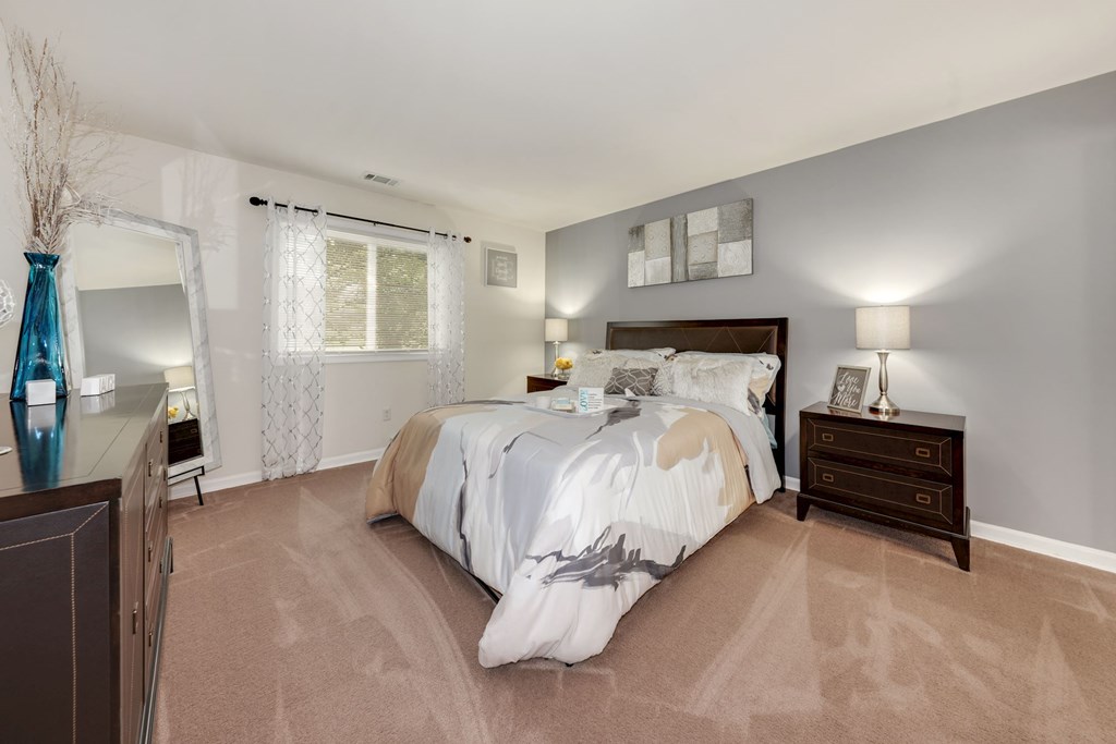 A bedroom with a large bed and a nightstand with a lamp.