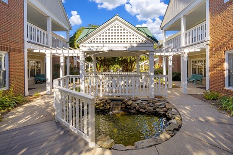 A gazebo with a fountain in the middle of a courtyard.