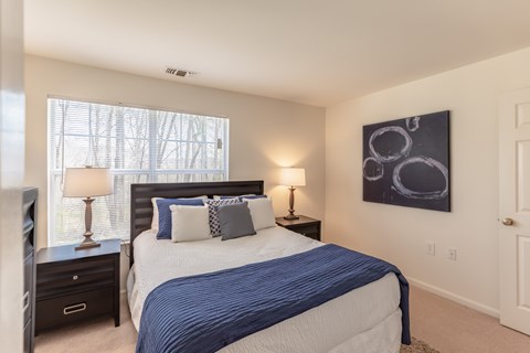 A bedroom with a large bed and a painting on the wall.