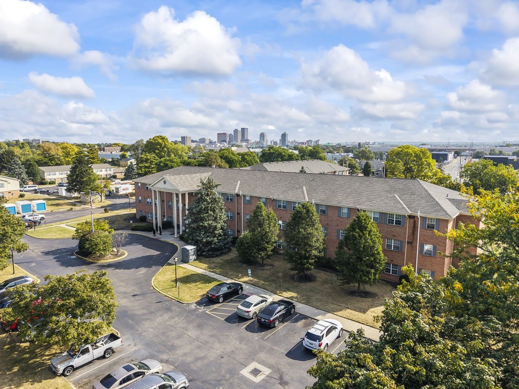 A parking lot in front of a building with a city skyline in the background.