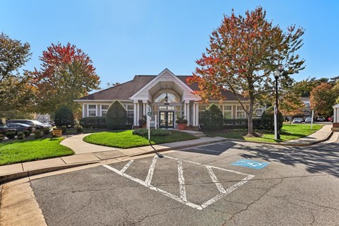 A large white building with a red roof and a tree with red leaves in front of it.