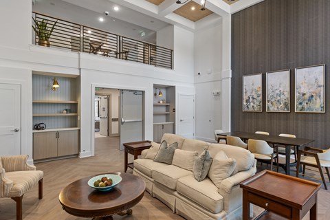 A living room with a couch, chairs, and a table with a bowl of fruit on it.