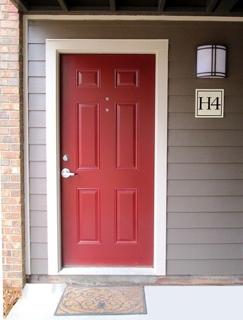 A red door with a white frame and a doorknob is on the front of a house.