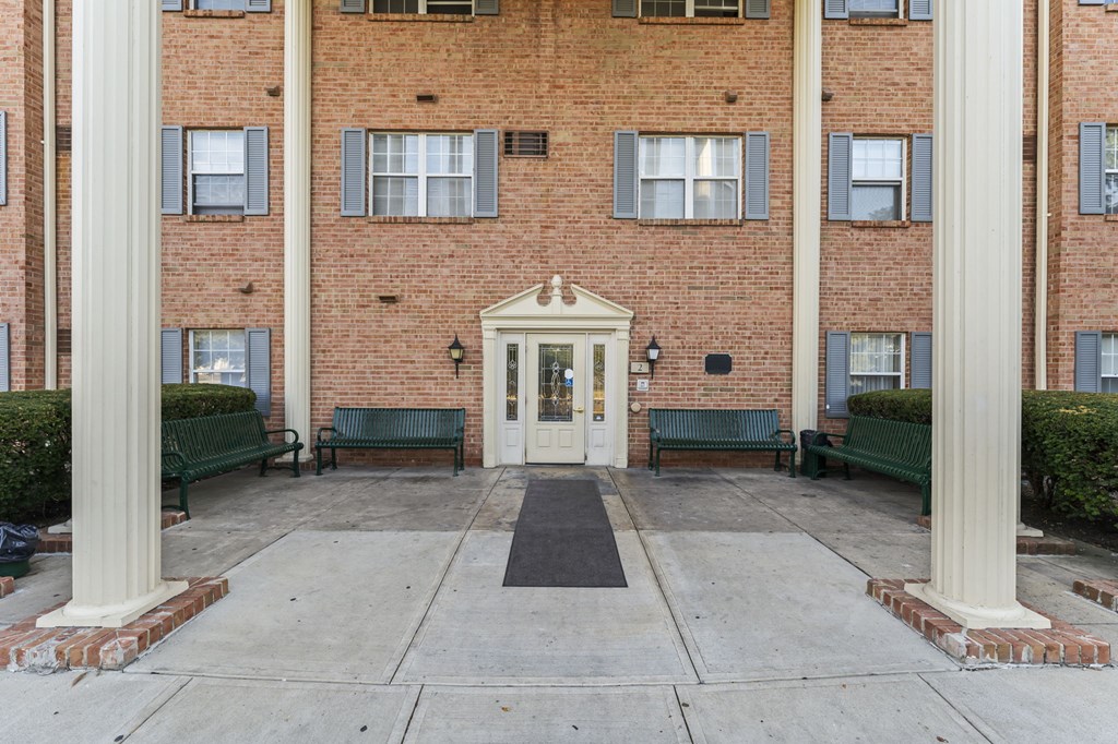 A building with a white door and two green benches in front.