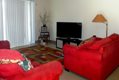 Two red couches in a living room with a flat screen TV.