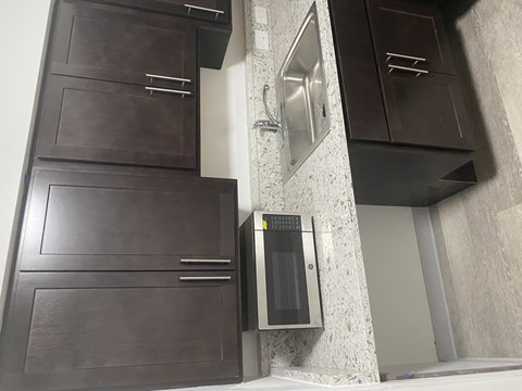 A kitchen with dark brown cabinets and a stainless steel oven.