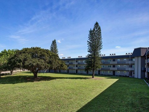 A grassy area in front of a building with trees.