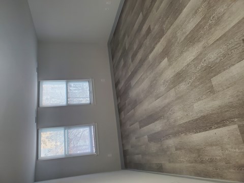 A room with a wooden wall and two windows.