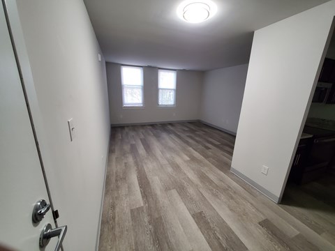 A room with wood flooring and a door on the left.