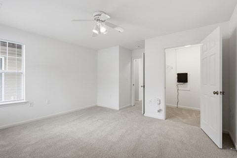 A spacious room with a ceiling fan and carpeted floor.