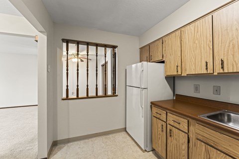 A kitchen with a white fridge and wooden cabinets.