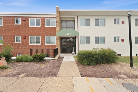 The front of apartment building 4527 with a black fence and bushes.