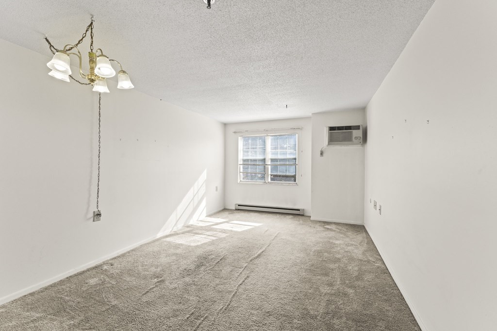 A room with a carpeted floor and a window with blinds.