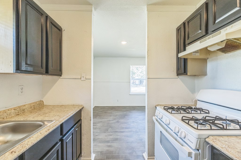 A kitchen with black cabinets and a white stove.