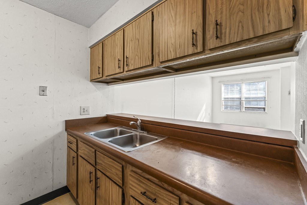 A kitchen with wooden cabinets and a white wall.