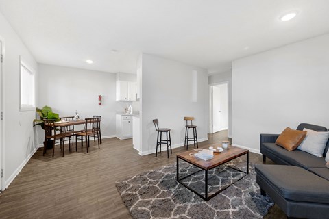 A living room with a grey couch, a coffee table, and a dining table with chairs.