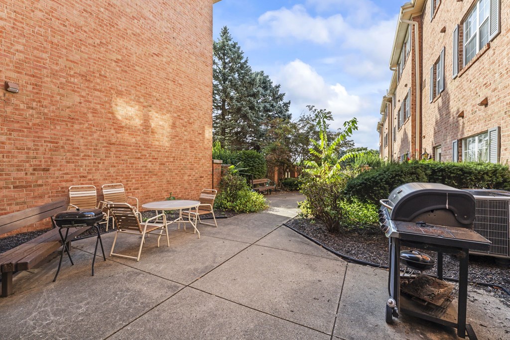 A patio with a table and chairs is surrounded by a brick wall.