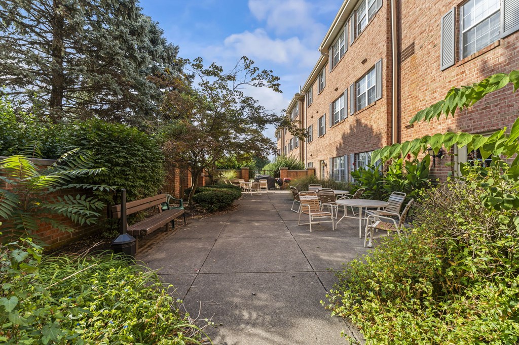 A sunny day at a brick apartment complex with a patio and chairs.