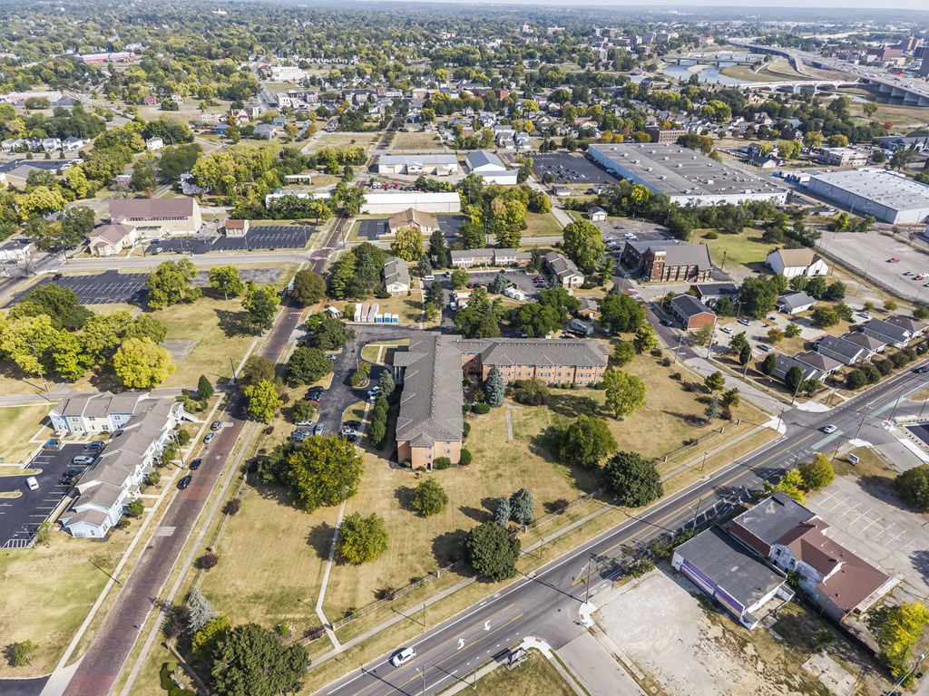 A bird's eye view of a suburban area with roads, buildings, and trees.