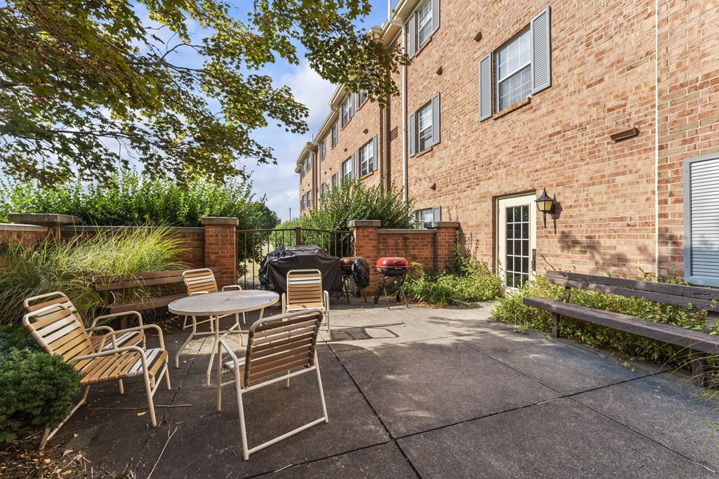 A patio with a table and chairs is surrounded by a brick building.