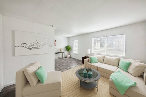 A living room with a beige couch, a glass coffee table, and a painting on the wall.
