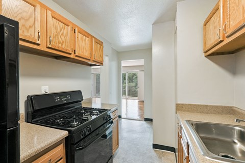 A kitchen with a black stove top oven and wooden cabinets.