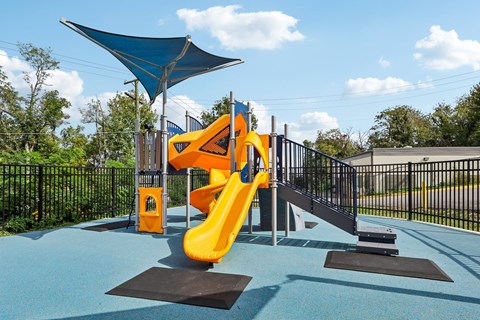 A playground with a yellow slide and a blue canopy.