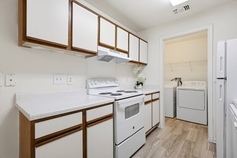 A white kitchen with a stove, oven, and refrigerator.