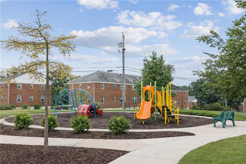 a playground in a park in front of a brick building