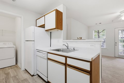 A white kitchen with wooden cabinets and appliances.