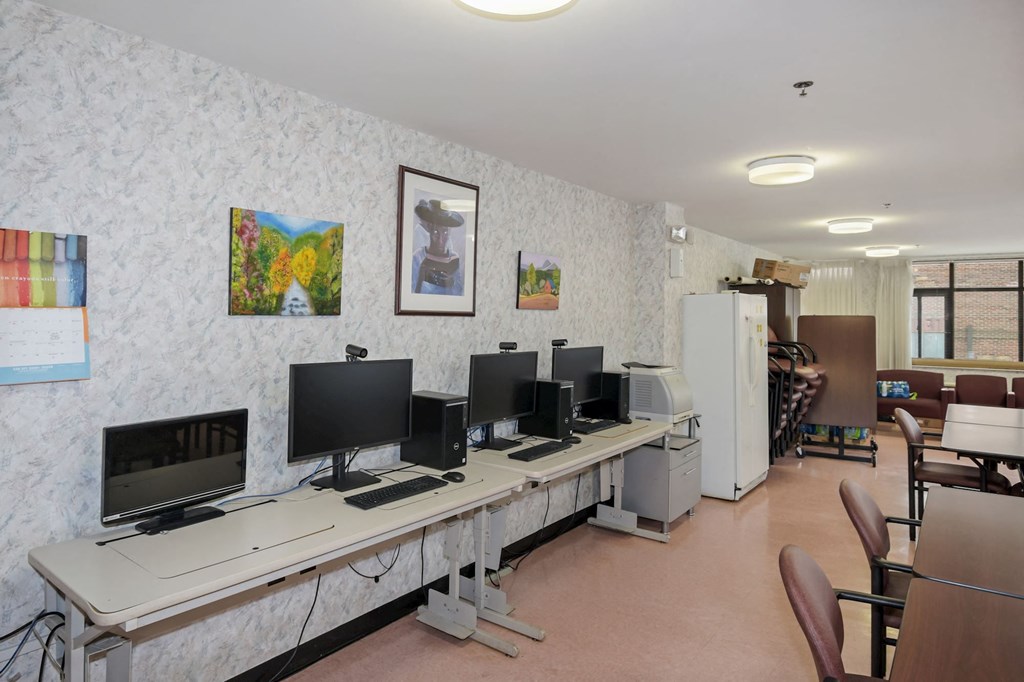 a computer room with several monitors on a long desk