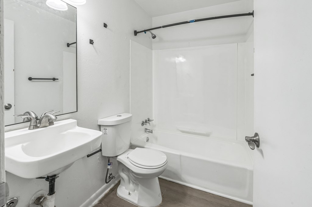 A white bathroom with a toilet, sink, and bathtub.