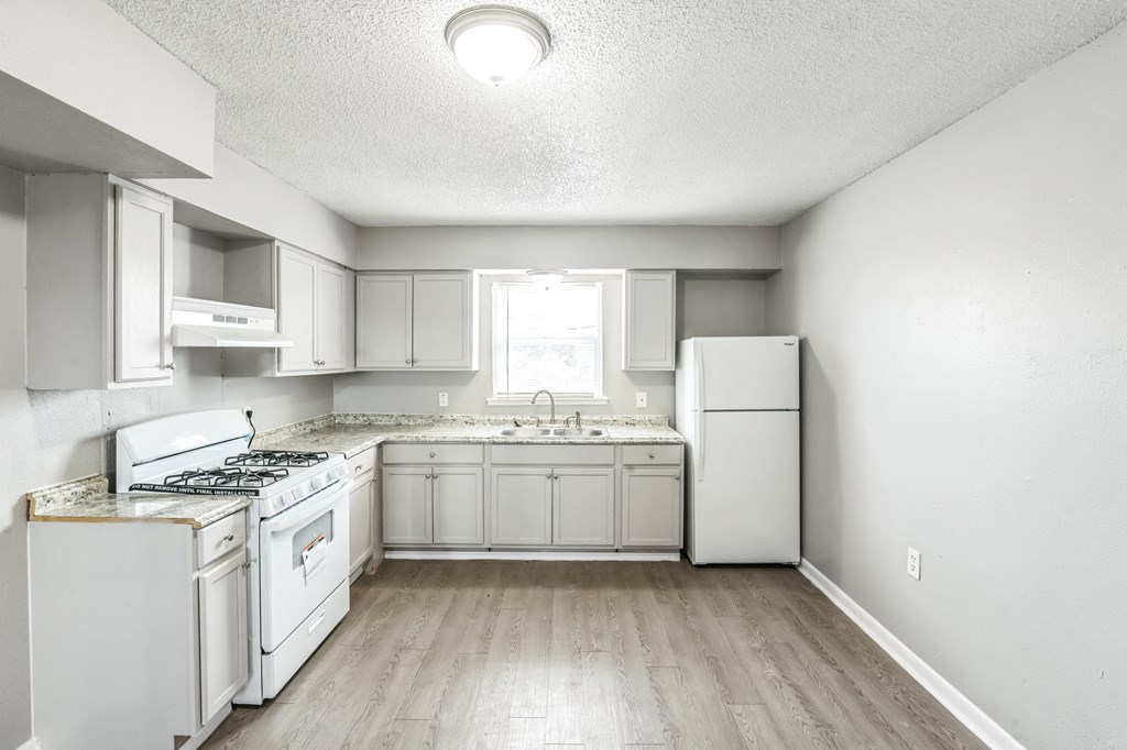 A white kitchen with a stove, sink, and refrigerator.